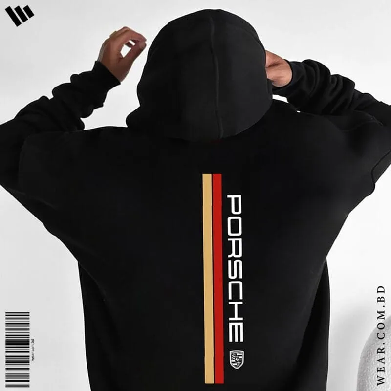 Back view of a man wearing a black oversized hoodie featuring a vertical red and gold stripe, the Porsche logo text, and the Porsche crest.