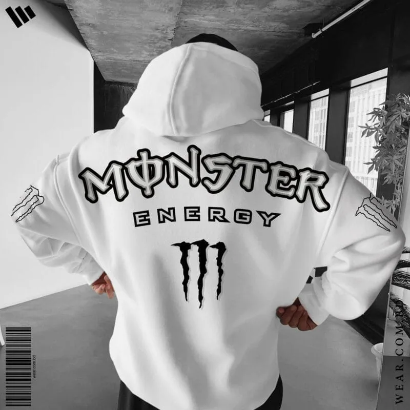 Back view of a man wearing a white oversized hoodie featuring the large Monster Energy text logo and M-claw graphic, with M-claw logos on the sleeves.