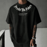 Front view of a man wearing a black oversized t-shirt with white text saying "Predict The Future" in gothic font, and "Success Final CONTINUE THAT COUNTS" below it.