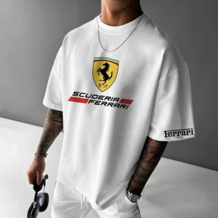 Front view of a man wearing a white oversized t-shirt with a large Scuderia Ferrari shield logo on the chest and "Ferrari" text on the left sleeve.